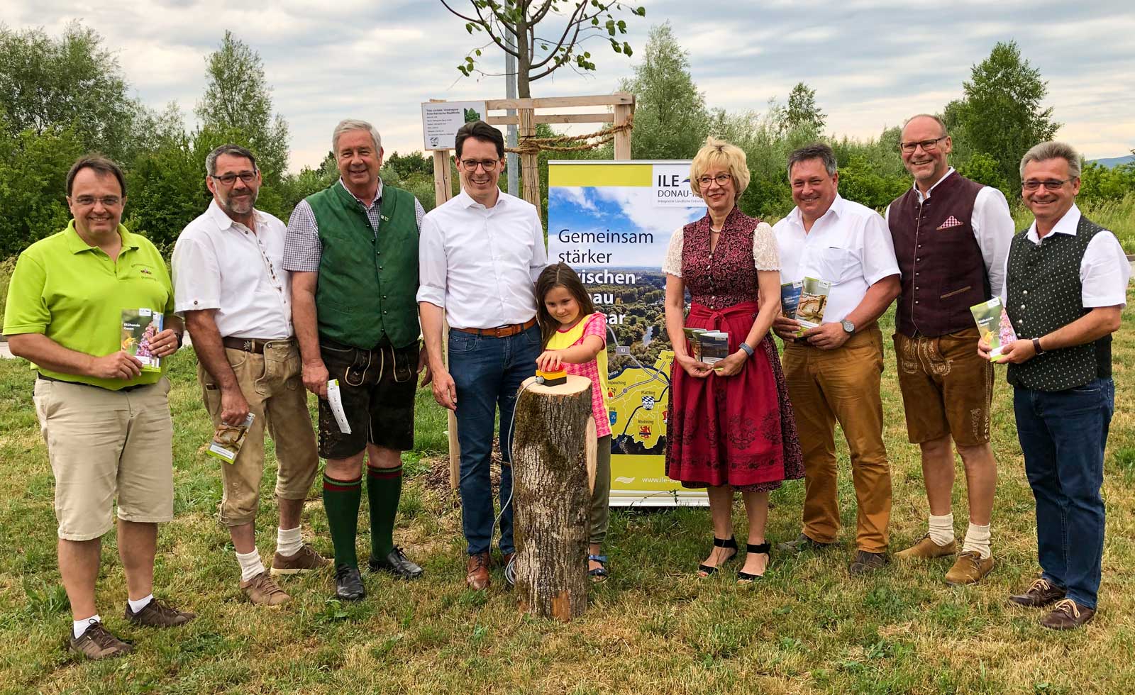 Symbolisch drückt Sophia auf den roten Knopf und schaltet damit die Internetseite www.ile-donau-isar.de frei. Die Verantwortlichen der ILE haben am Donnerstagabend auf einer Blühfläche im Plattlinger Gewerbegebiet außerdem drei Info-Faltblätter zu den Themen Blühflächen, Lebensmittelerlebnisse und Wasserwelten vorgestellt. Von links: Rochus Gold, Vorsitzender des Bienenzuchtvereins Plattling, Erster Bürgermeister Martin Betzinger, Aholming, Erster Bürgermeister Erich Schmid, Plattling, Oberbürgermeister Dr. Christian Moser, Deggendorf, mit Tochter Sophia, Erste Bürgermeisterin und ILE-Vorsitzende Jutta Staudinger, Stephansposching, Ester Bürgermeister Johannes Schmid, Otzing, Geschäftsleiter Wilhelm Schmid, Stephansposching, und Geschäftsleiter Josef Hofmeister, Plattling. (Foto: Christian Omonsky)